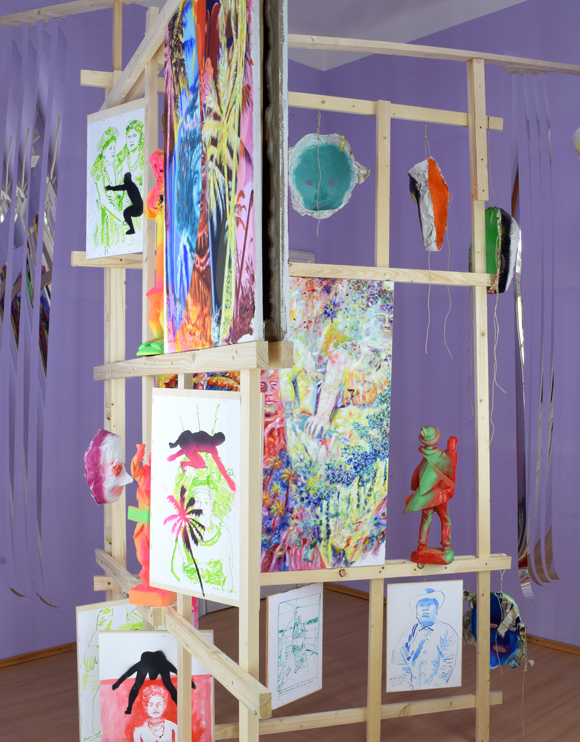 Martin von Ostrowski: Koloniale Fragmente, Detail der Installation, 
						Holzlatten, Schrauben, 
						6 Gemälden je 80 x 60 cm, 2 Gemälden je 105 x 85 cm,                    
						10 gefassten Holzskulpturen bis 57 cm Höhe, 28 Tuschezeichnungen 
						teilweise mit  Sprühlack bearbeitet auf Holzplatten getackert, je 42,0 x 29,7 cm, 
						10 gefasste Maskenabformungen aus Pappmaché, Maße 2,7 x 4,5 x 5,0 m