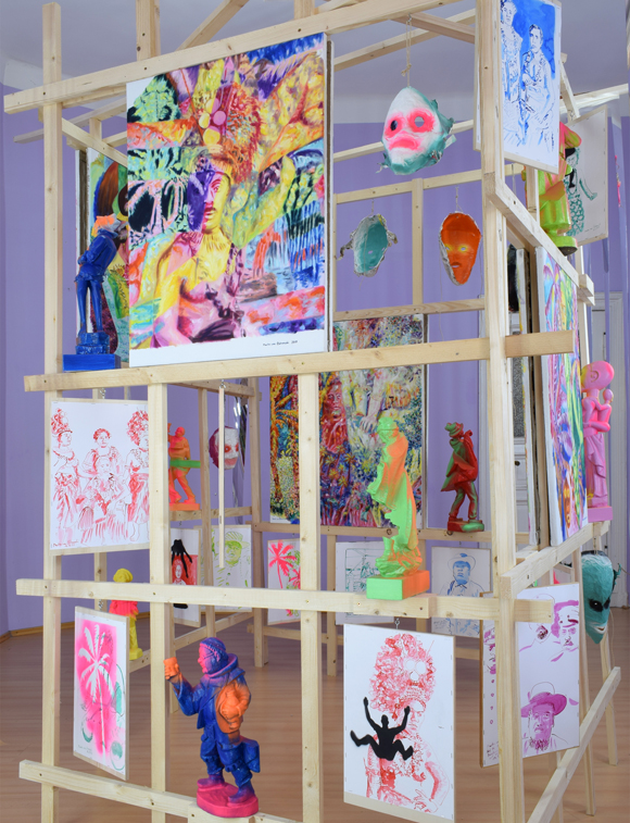 Martin von Ostrowski: Koloniale Fragmente, Detail der Installation, 
						Holzlatten, Schrauben, 
						6 Gemälden je 80 x 60 cm, 2 Gemälden je 105 x 85 cm,                    
						10 gefassten Holzskulpturen bis 57 cm Höhe, 28 Tuschezeichnungen 
						teilweise mit  Sprühlack bearbeitet auf Holzplatten getackert, je 42,0 x 29,7 cm, 
						10 gefasste Maskenabformungen aus Pappmaché, Maße 2,7 x 4,5 x 5,0 