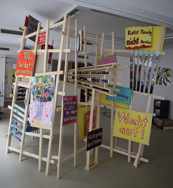 Martin von Ostrowski: P-Zickzack, 2017, Installation aus 4 Holzgittern (je 240x150x5 cm), 4 Ölgemälden (je 80x60cm), 
						5 in Streifen zerschnittenen Fotos (je 75x50 cm), 
						8 gefaltete Fotos (je 30x42 cm), 20 bemalte Kartonschilder,  
						Gesamtmaße der Installation: 240cm (Höhe), 400 cm (Länge), 150 cm (Tiefe)